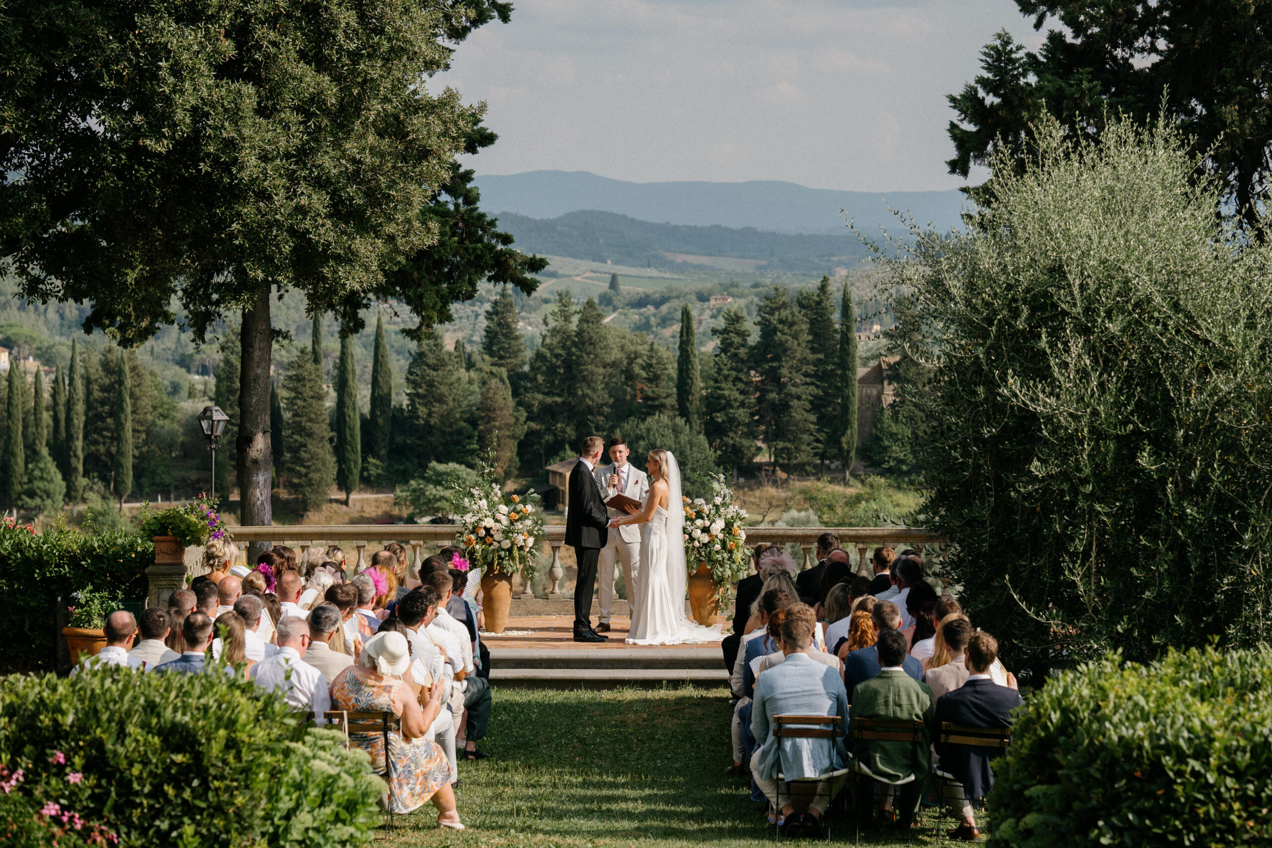 Gillian and Ross exchanging vows on a terrace with 30 km of rolling Tuscan vineyards behind them.